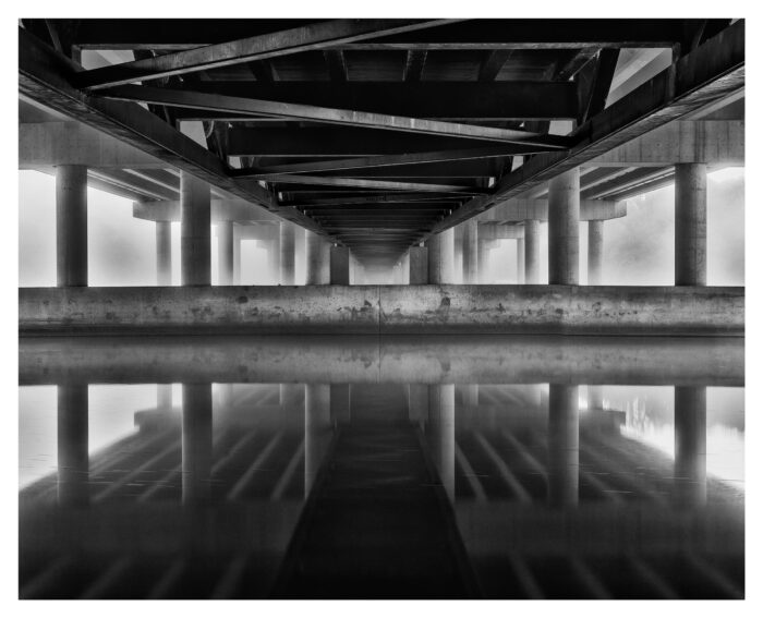 black and white image of bridge in fog